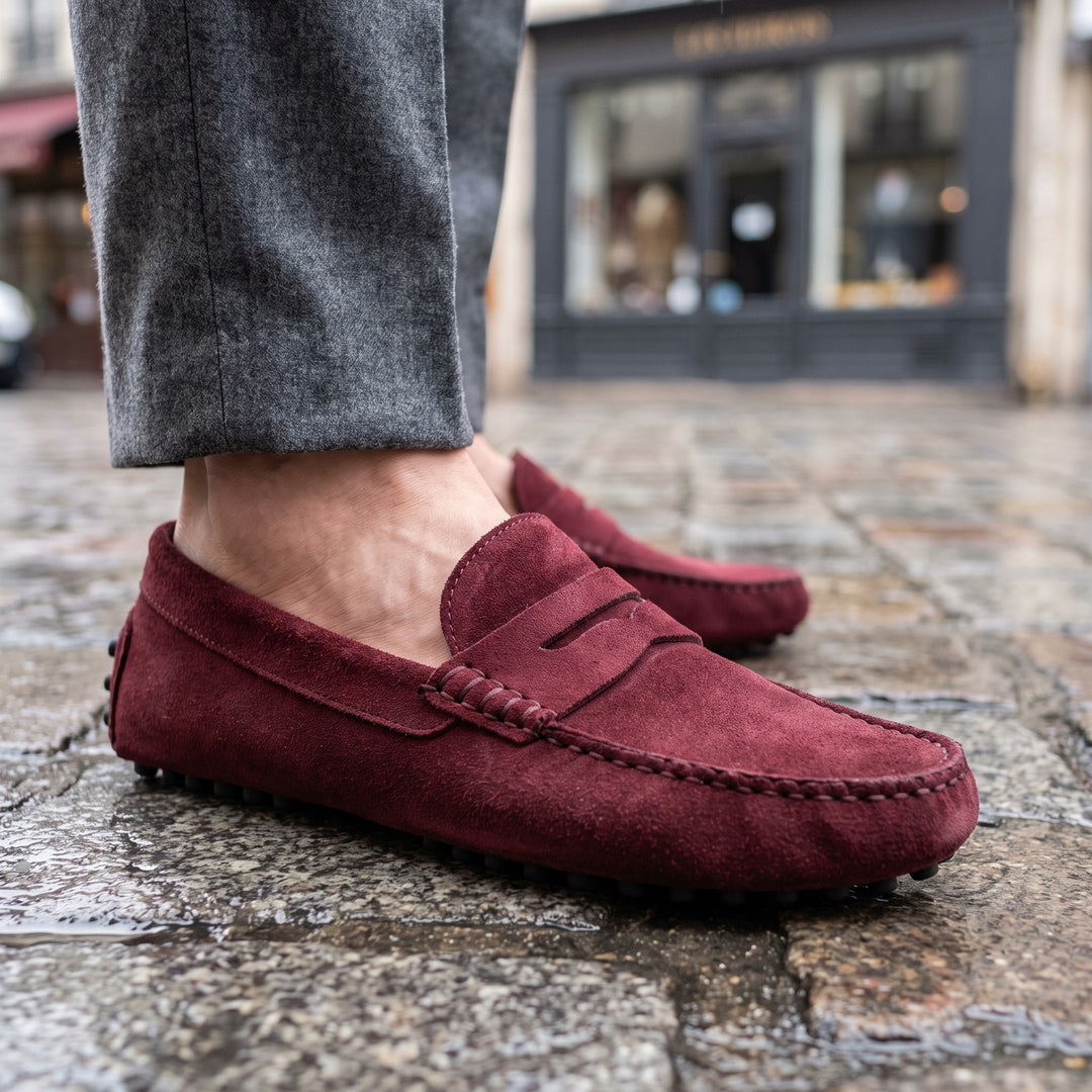 mocassin en daim bordeaux porté avec un pantalon de flanelle grise sur des pavés parisiens humides